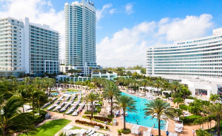 Mid Beach Miami wide pale sand and calm blue Atlantic backed by tall oceanfront hotels and the boardwalk