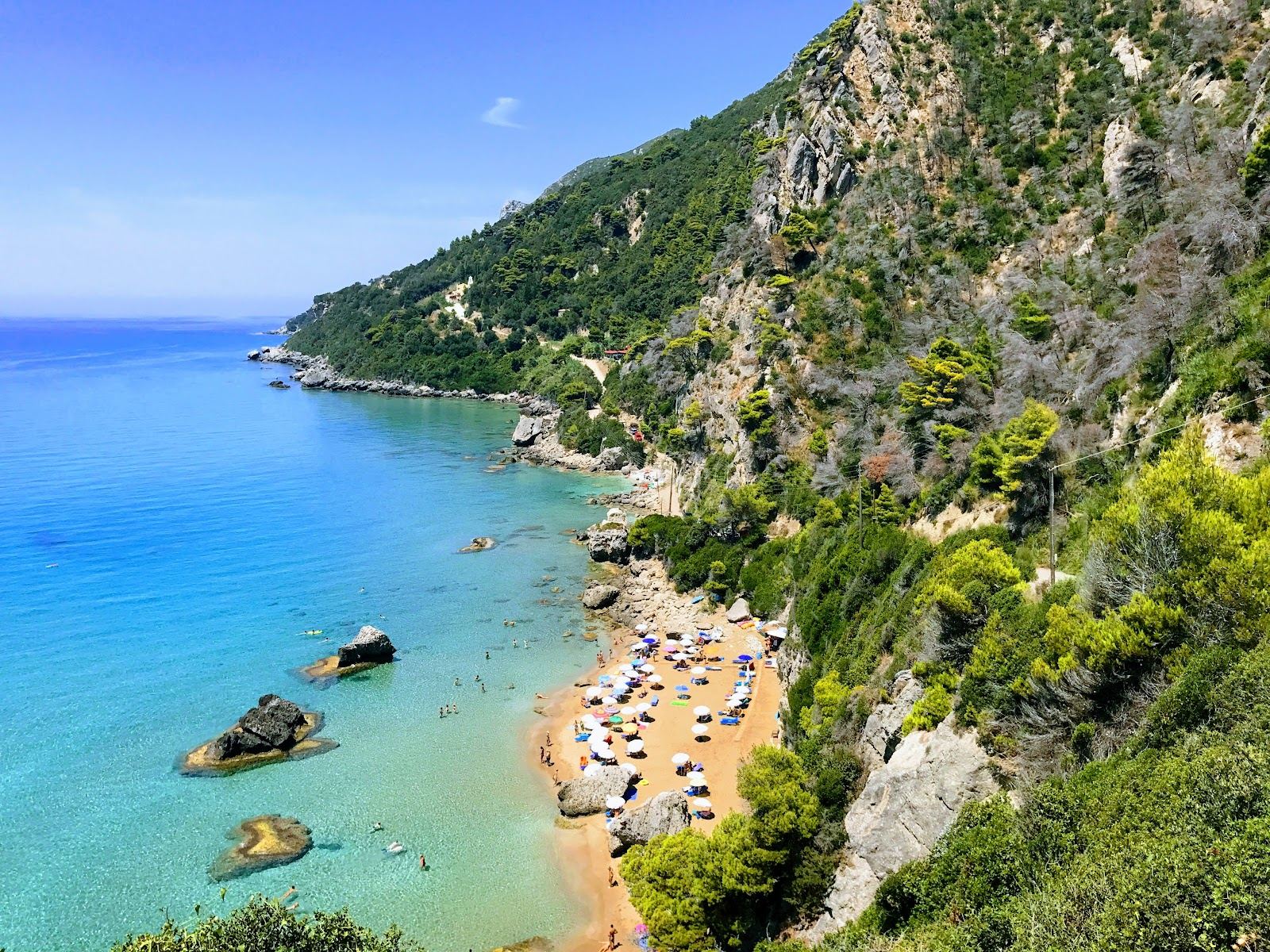 Soft golden sand under steep green cliffs at Myrtiotissa on the west coast of Corfu