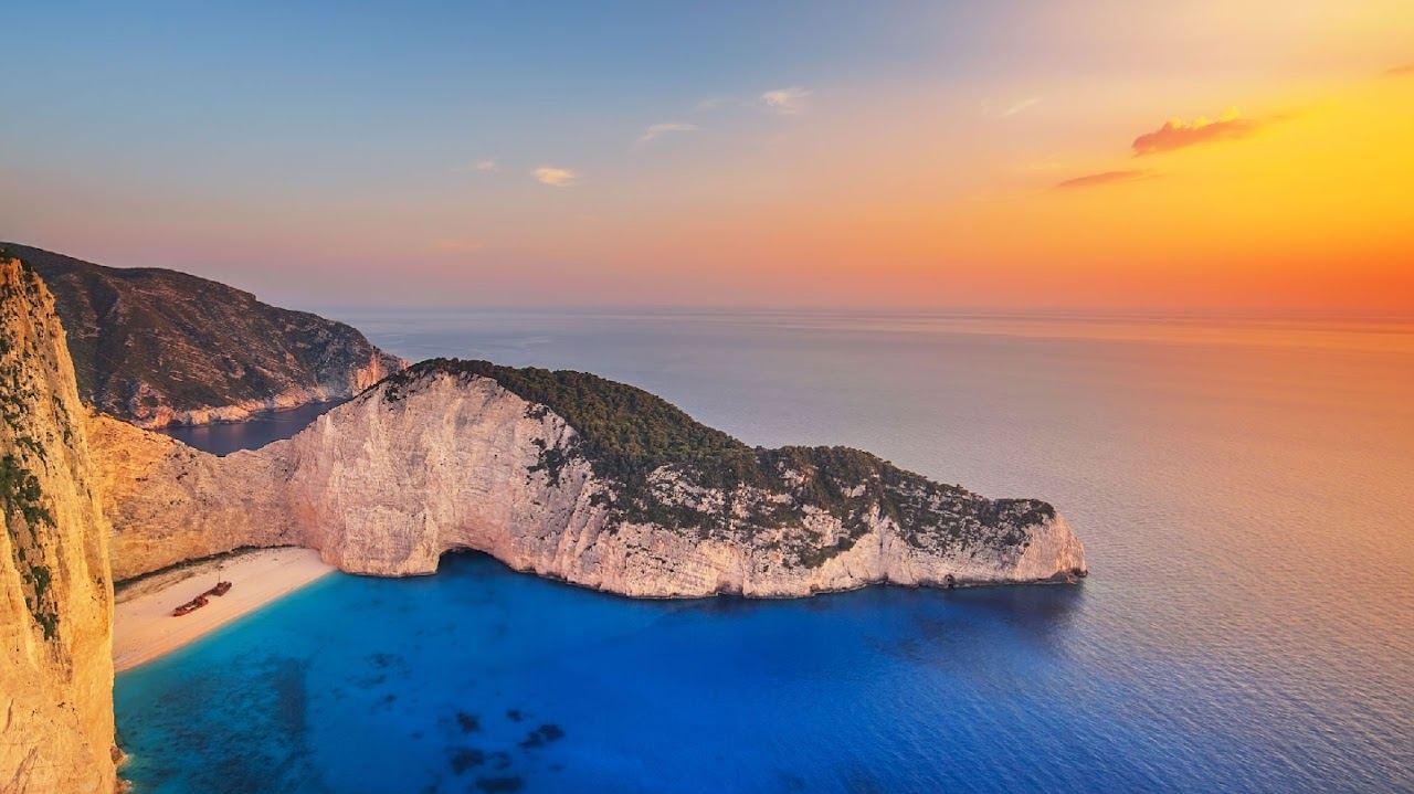 The rusting shipwreck on white shingle below sheer white cliffs at Navagio cove on the northwest coast of Zakynthos