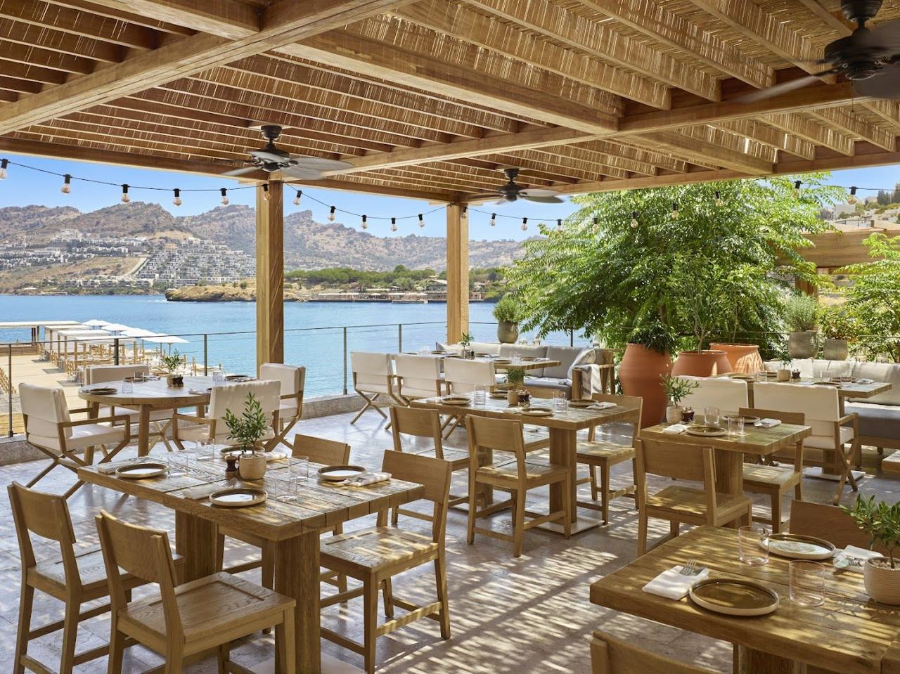 A refined beach club with loungers on a calm turquoise bay at The Bodrum Edition