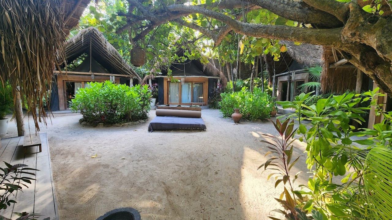 A bohemian beach club with daybeds and natural shades on the white sand at Tulum
