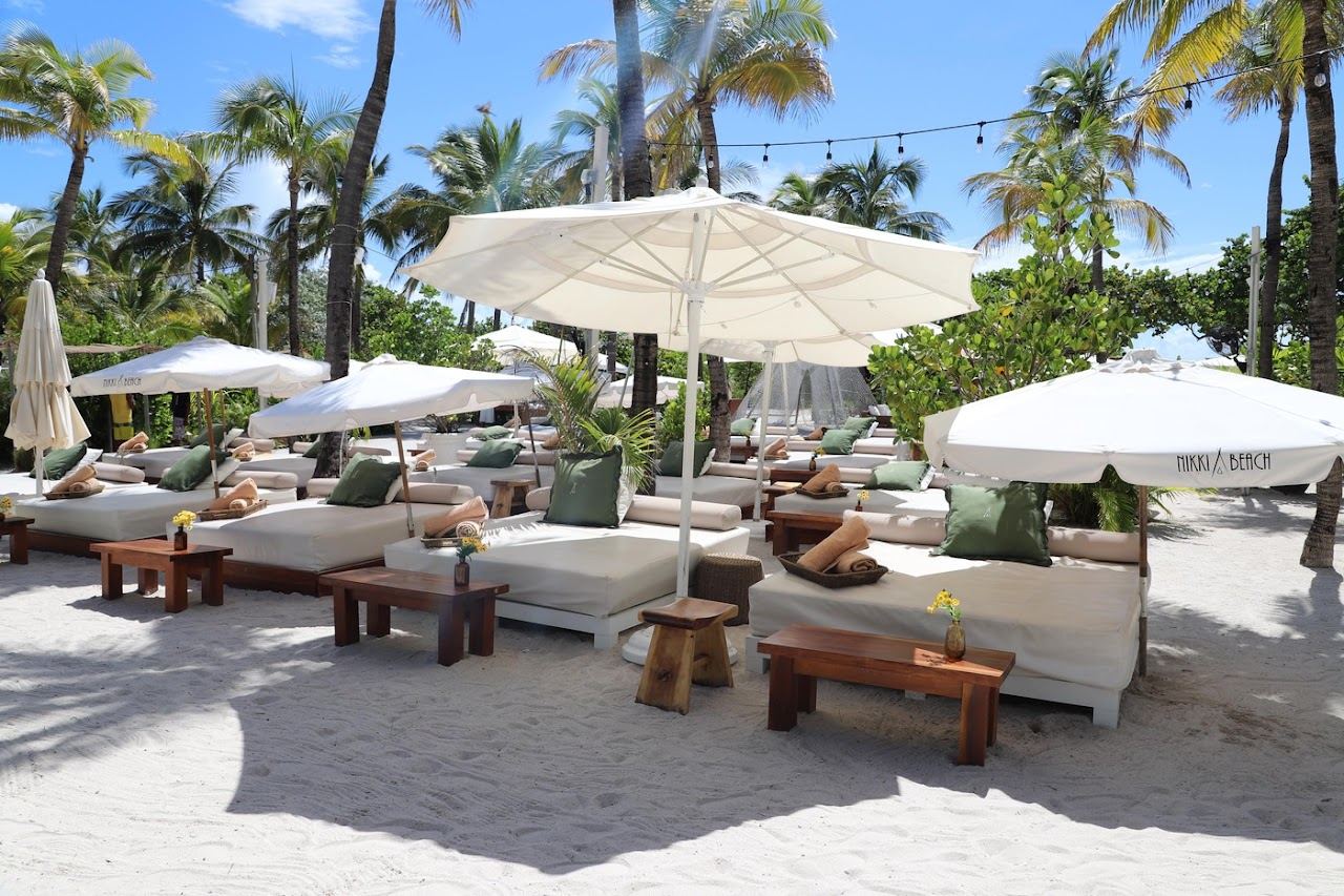 White daybeds and umbrellas on the sand at Nikki Beach Miami Beach at 1 Ocean Drive on South Beach
