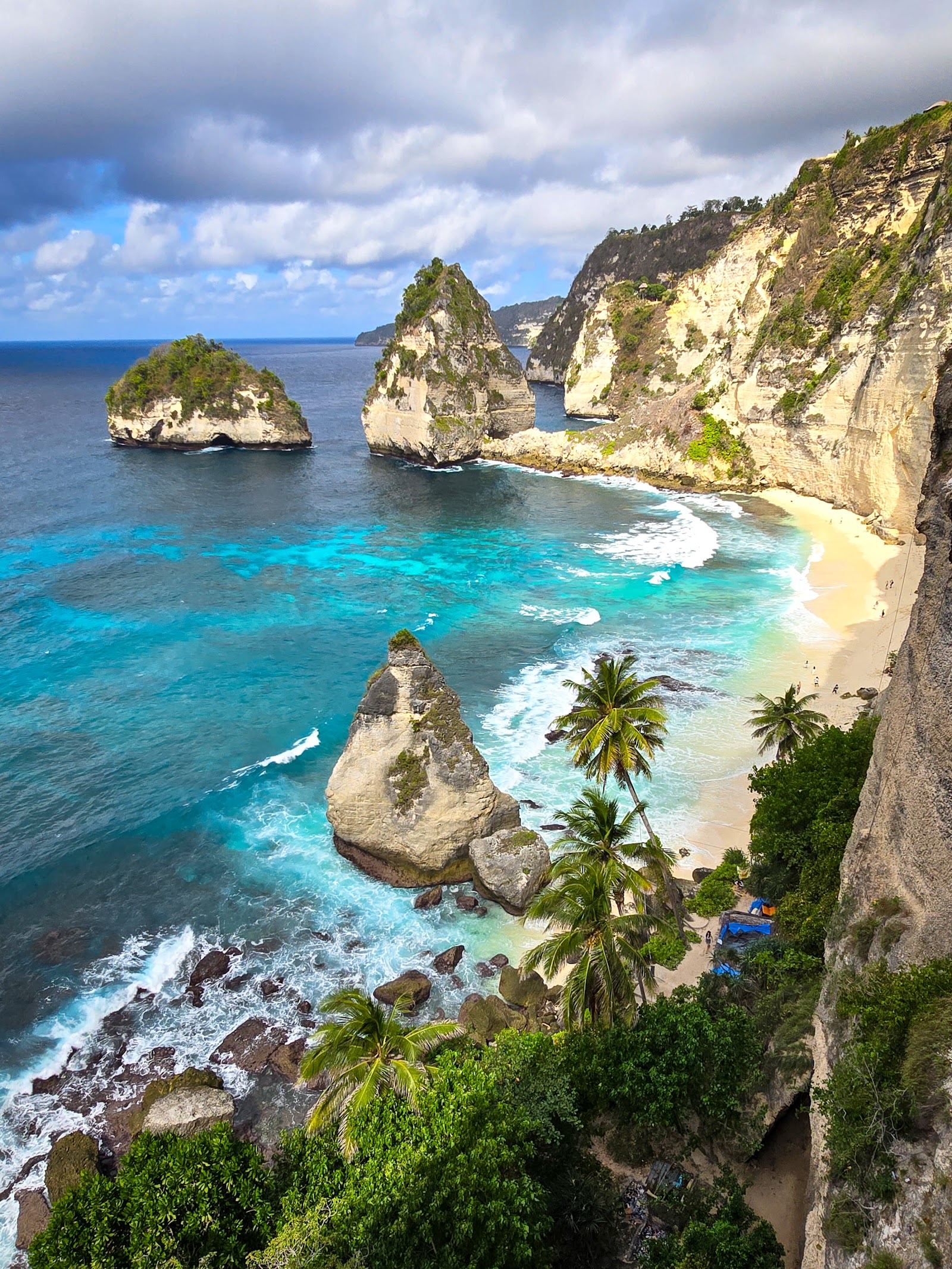 A white sand cove framed by carved limestone cliffs on Nusa Penida