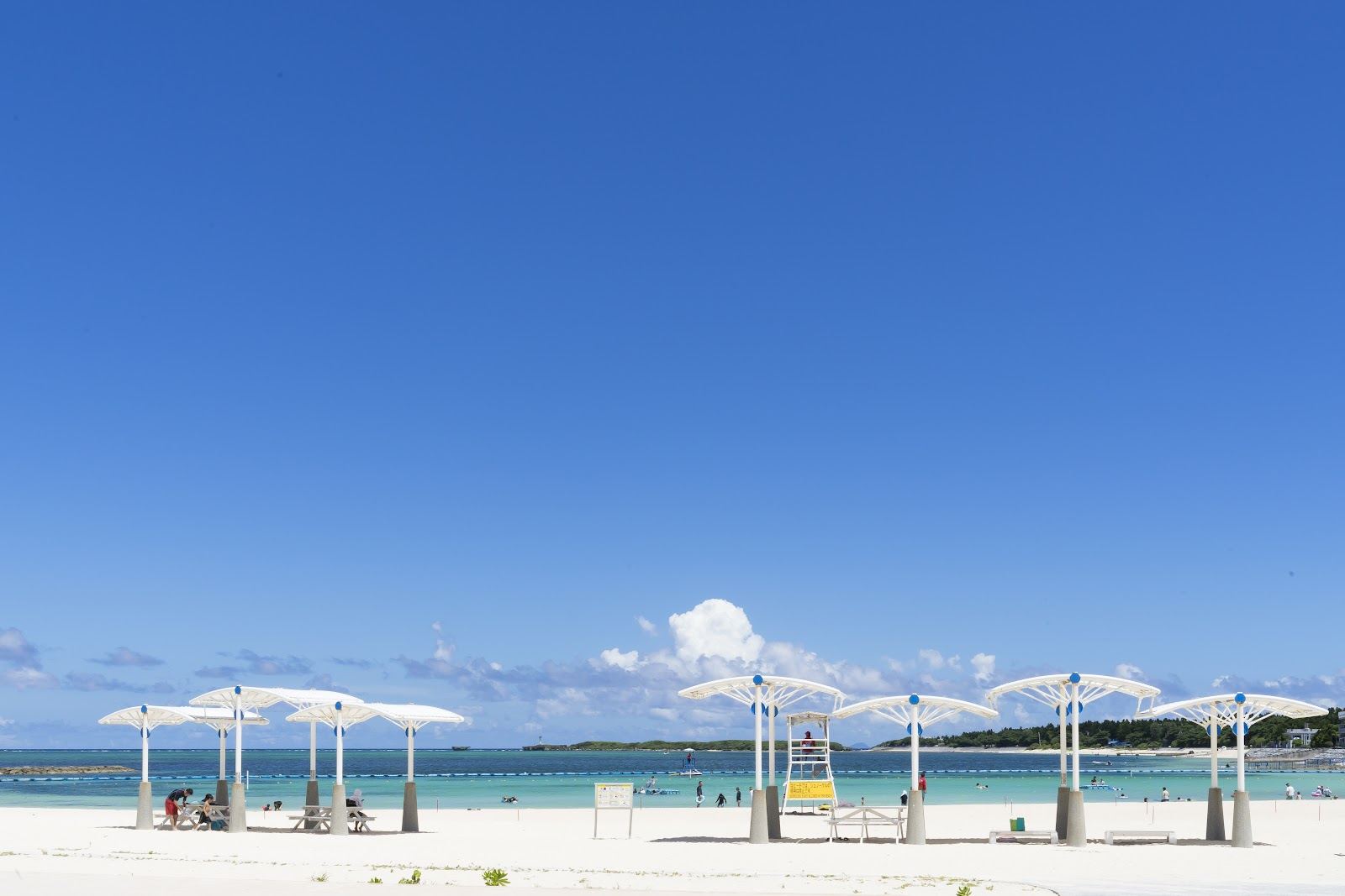Sheltered turquoise lagoon water and pale sand on a calm Okinawa beach