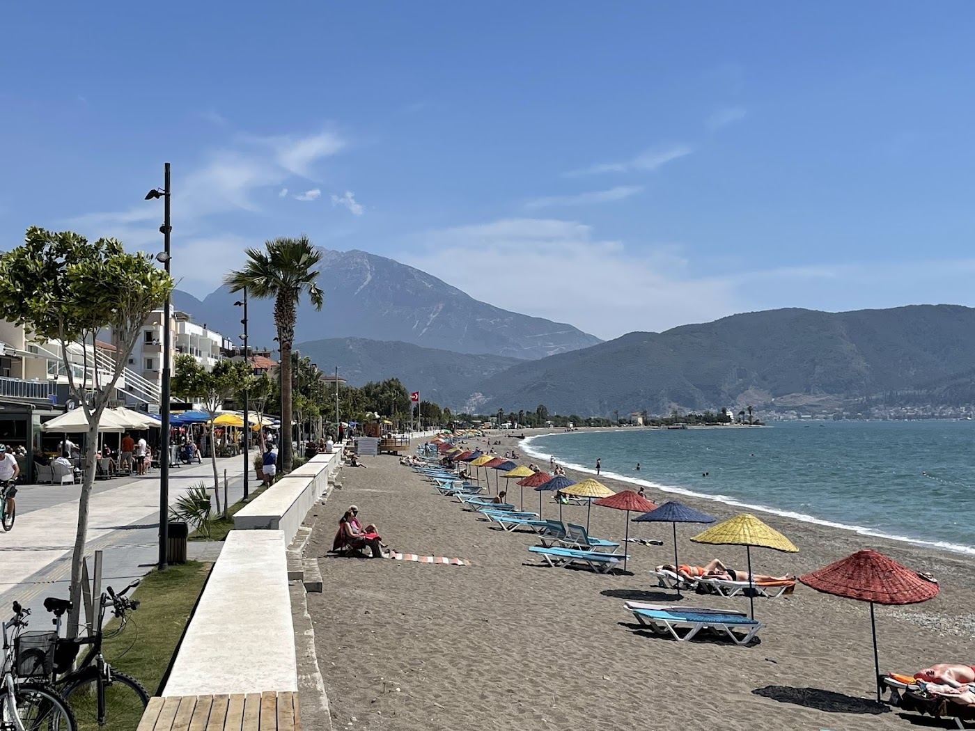 The long pebble beach and seafront promenade at Calis near Fethiye glowing at sunset with mountains behind in Turkey