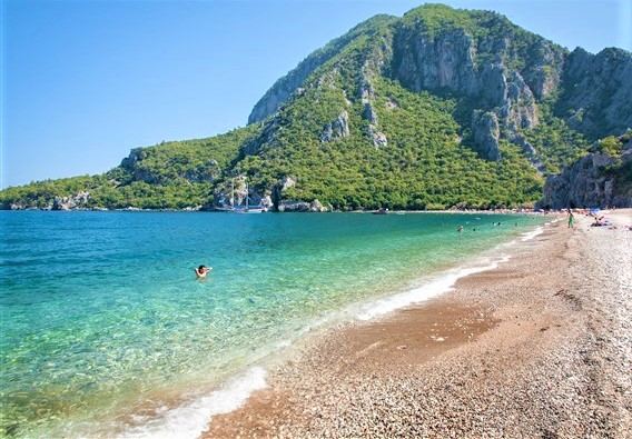 The quiet pebble and coarse sand shore of Olympos beach near Antalya backed by green hills