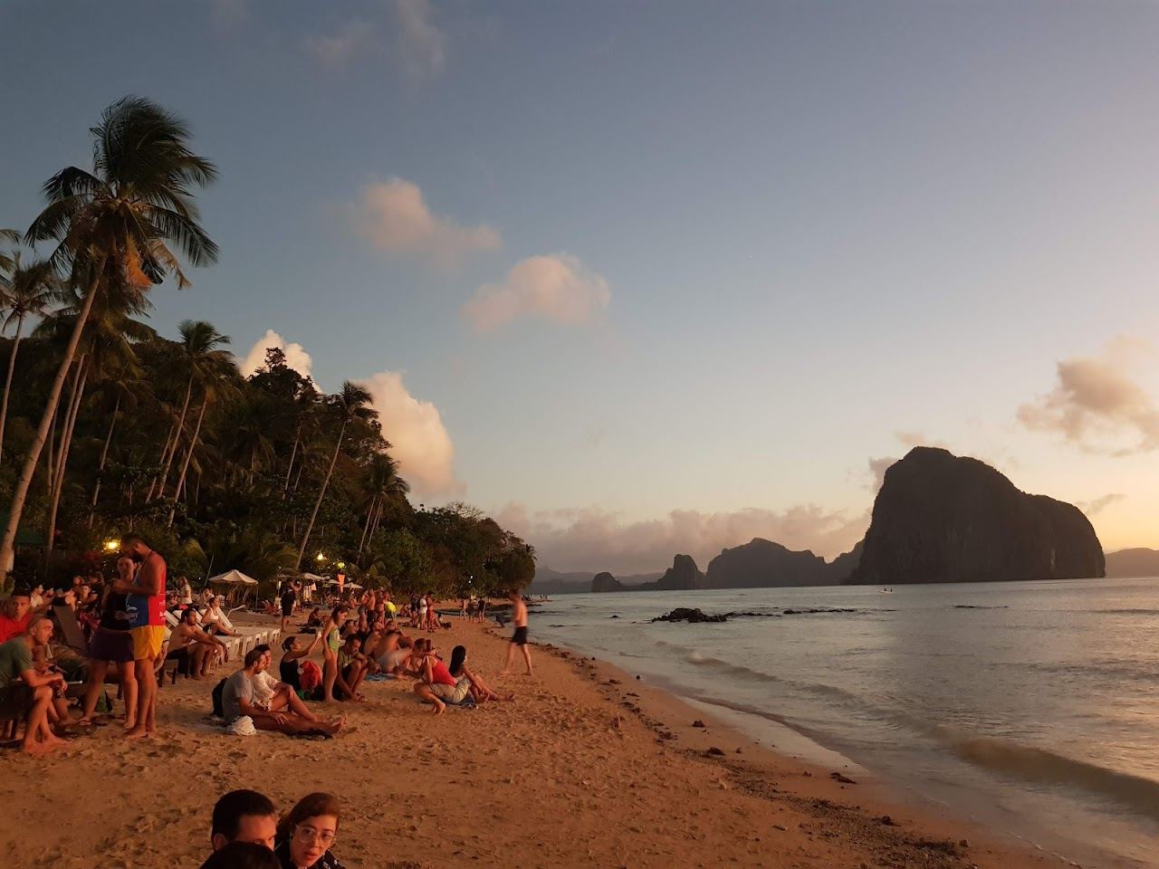 The west facing sand of Las Cabanas Beach near El Nido in Palawan glowing as the sun drops over the bay islands