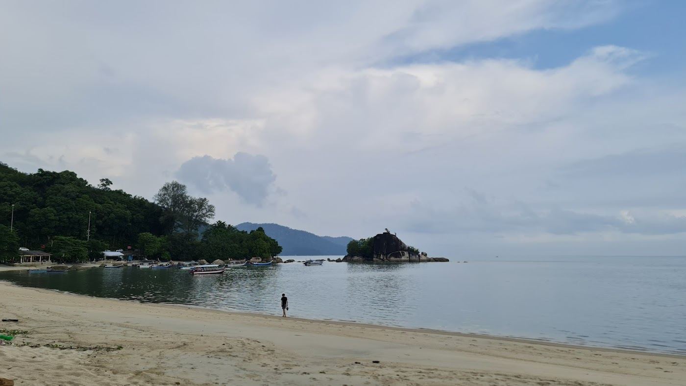 Sandy bay and warm sea on the north coast of Penang island below forested hills