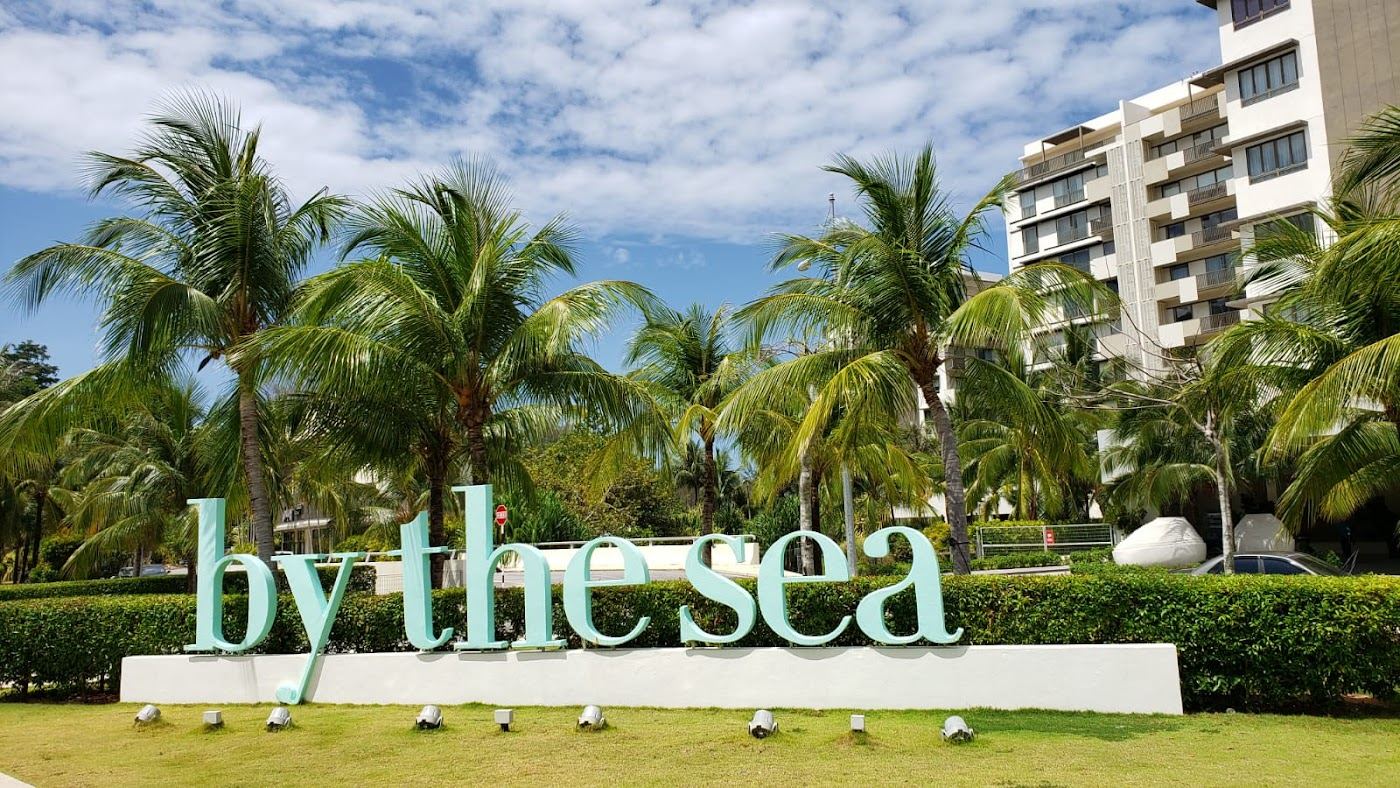 Warm sea and sandy beach below green hills on the coast of Penang island
