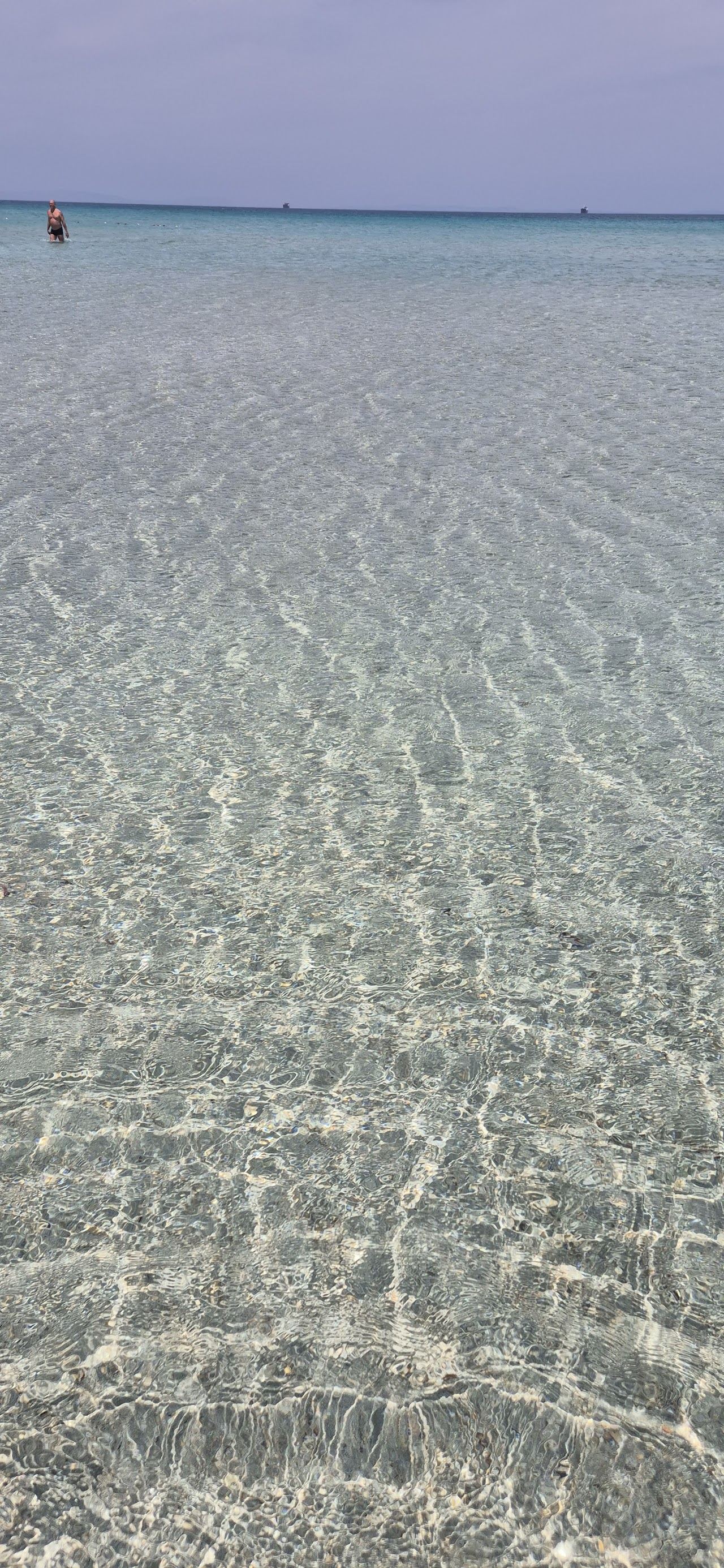 Wide pale sand and shallow turquoise water on the exposed western point at Pirlanta Beach in Cesme