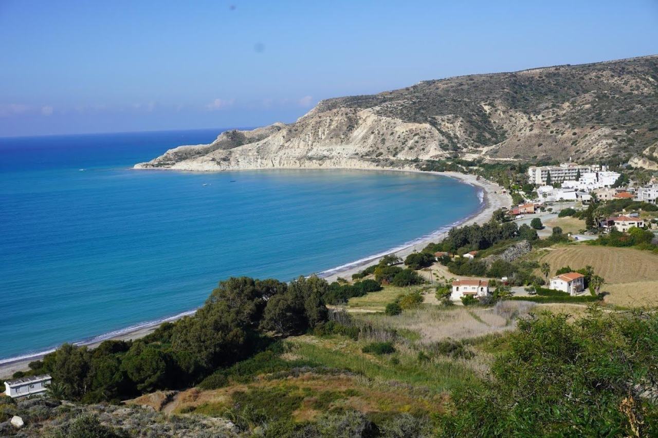 Clear water lapping the sheltered curve of Pissouri Bay framed by green hills on the south coast of Cyprus