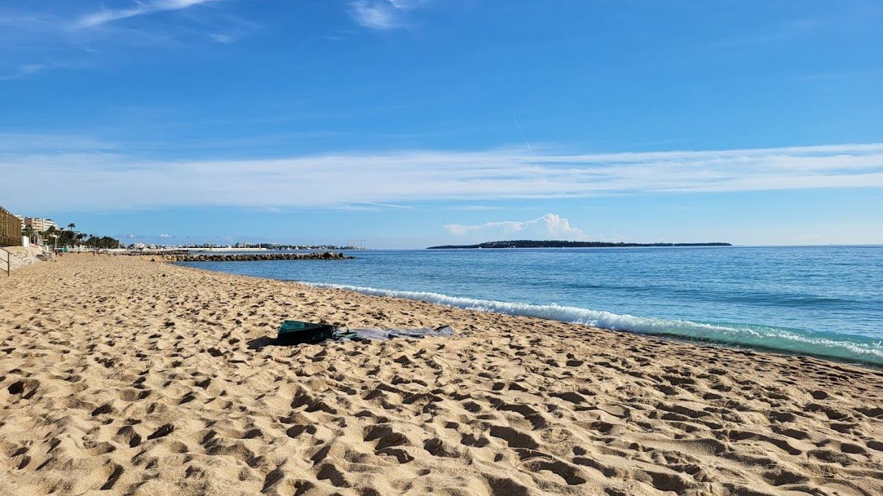 Long sandy Plage du Midi west of the old port in Cannes with calm sea and southwest light