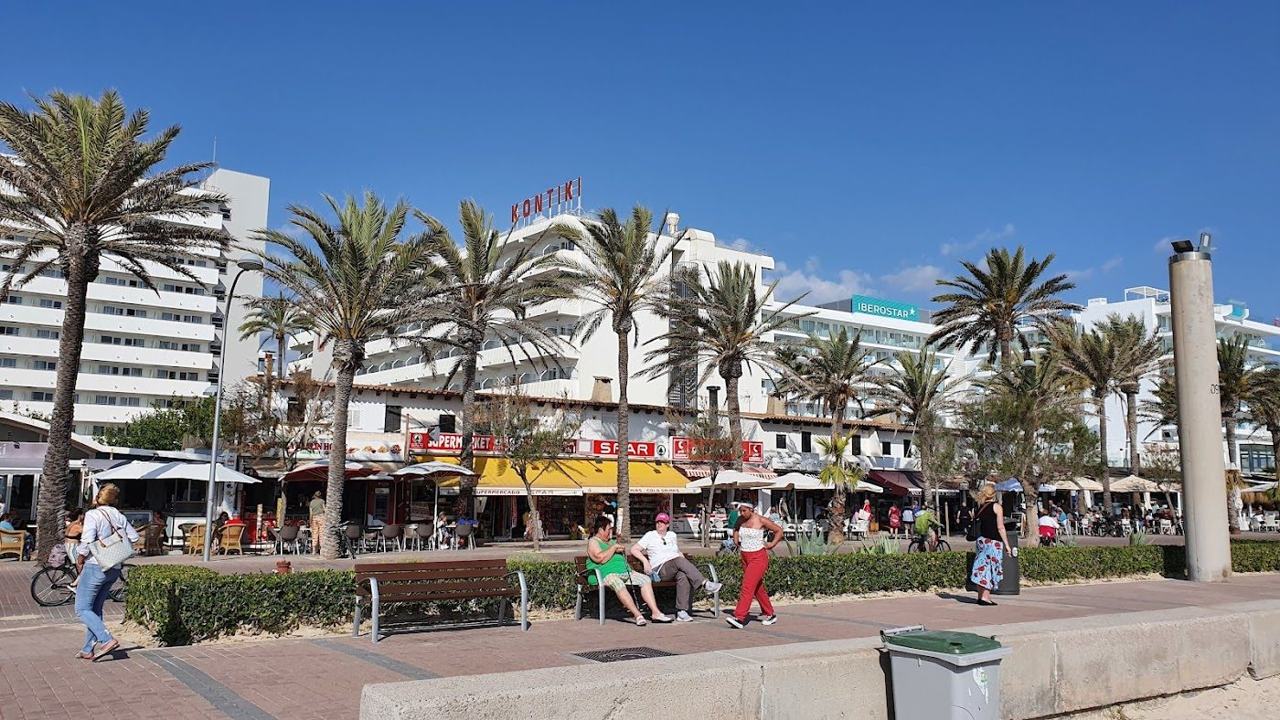 The wide golden sand and palm lined promenade of Playa de Palma running along the bay in Mallorca