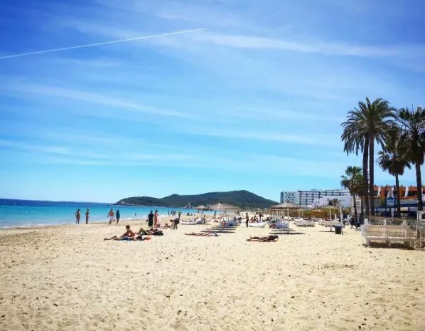 The long golden sand and shallow water of Playa d'en Bossa with beach clubs along the shore in Ibiza