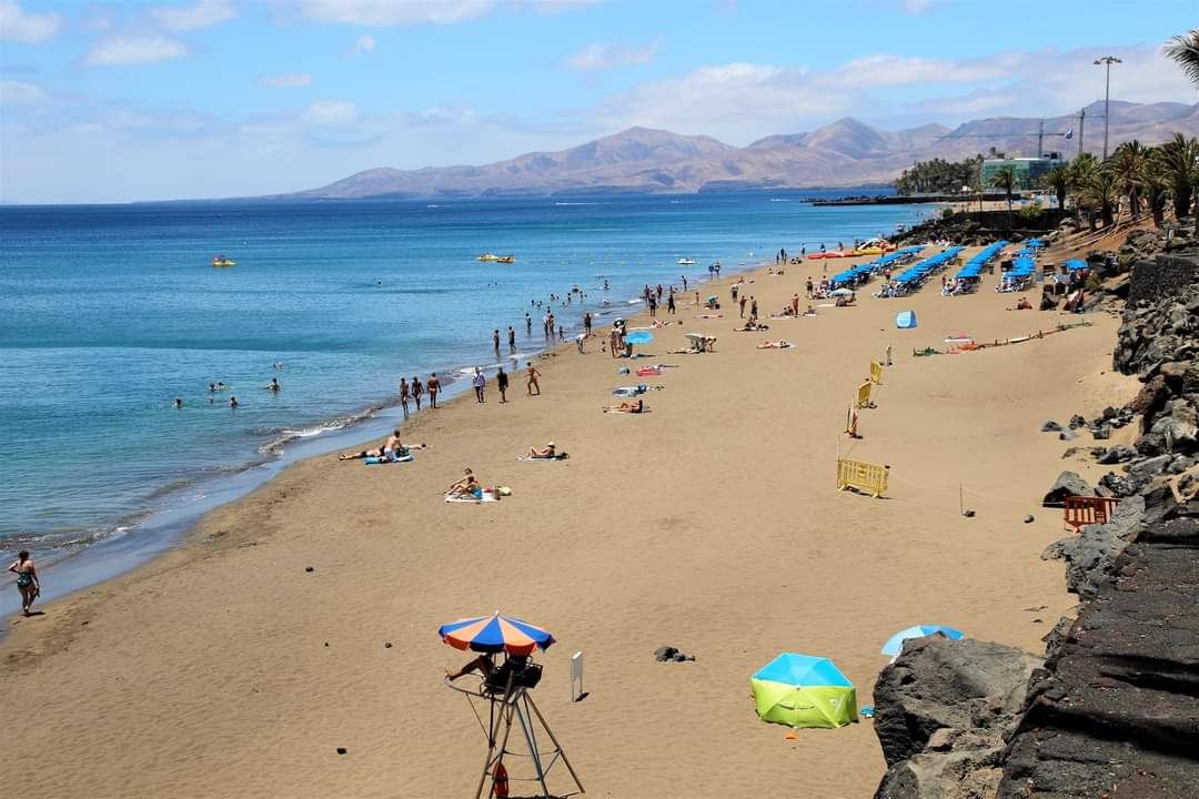 Long golden main resort beach with sunbeds and crowds at Playa Grande in Puerto del Carmen, Lanzarote
