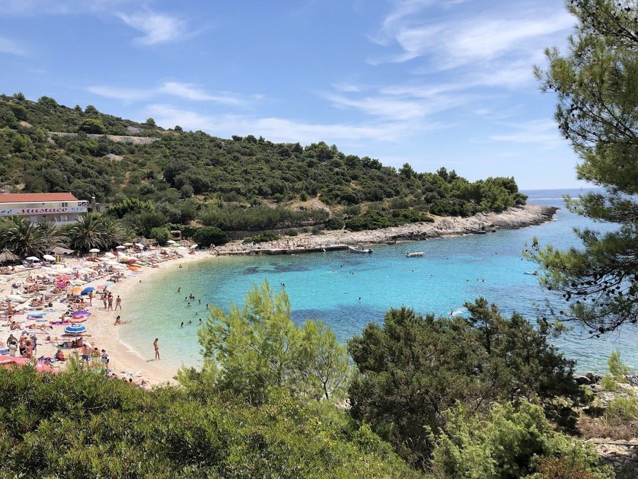 Pokonji Dol pebble beach near Hvar town facing a small lighthouse islet with clear water on the Dalmatian Coast