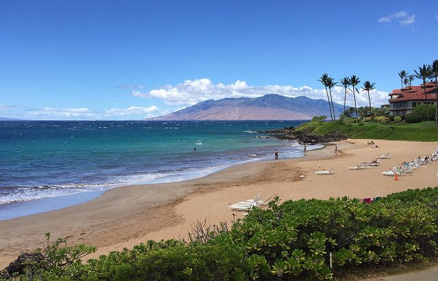 Polo Beach Wailea Maui a golden beach with calm clear water fronting a resort with lava rocks at one end