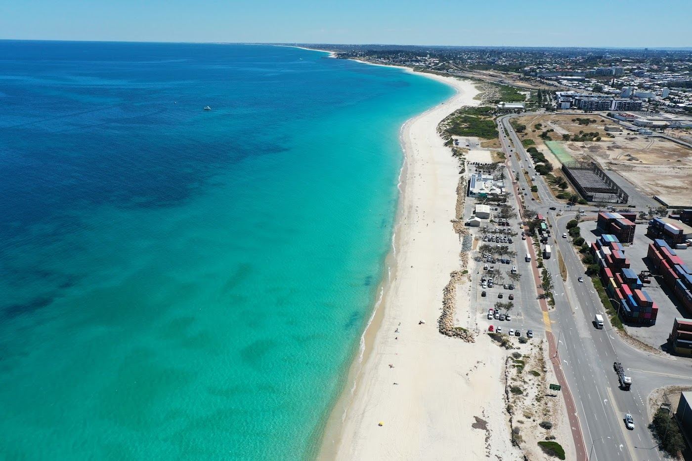 The wide pale sand and calm morning water of Port Beach in North Fremantle, Western Australia