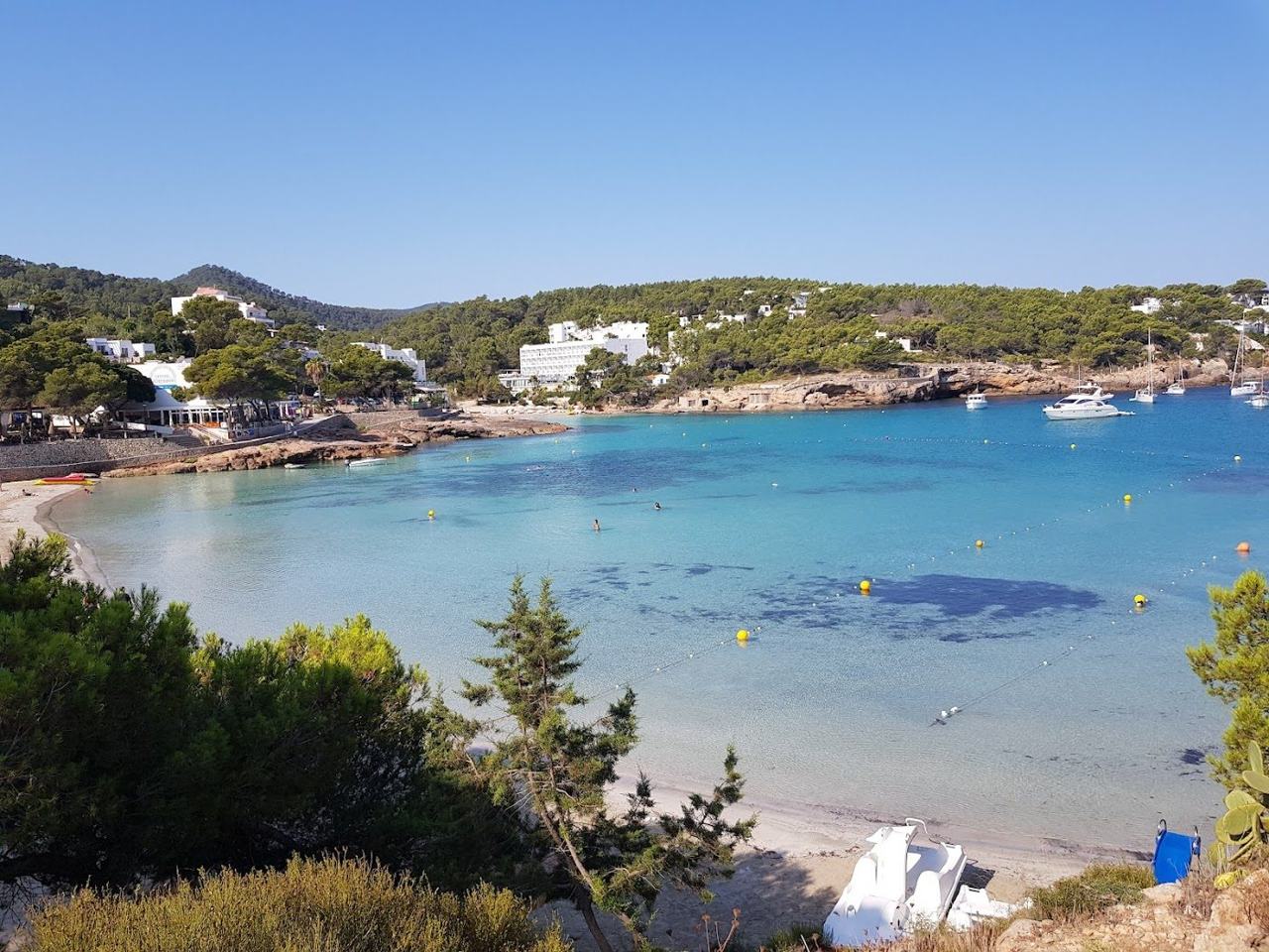 A sheltered sandy cove with clear shallow water at the Portinatx resort in the far north of Ibiza