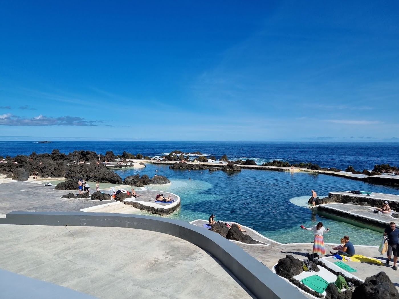 Clear blue seawater cupped in jagged black lava rock at the natural swimming pools of Porto Moniz on the northwest tip of Madeira
