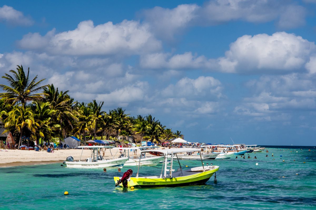 The pier, fishing boats and calm water at the town beach of Puerto Morelos in the Riviera Maya