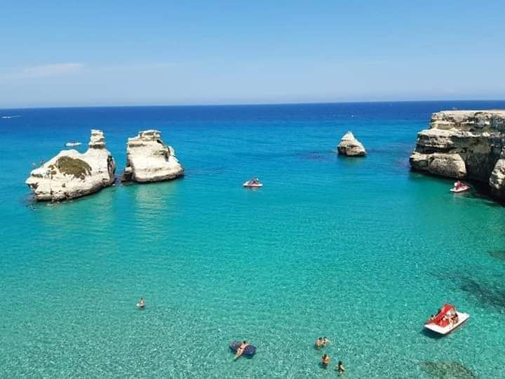 The wide sandy bay of Torre dell'Orso framed by low cliffs and pine on the Adriatic coast of the Salento in Puglia