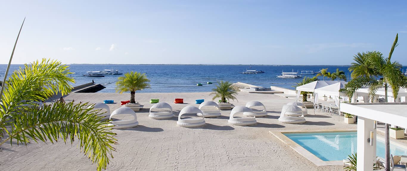 Resort beachfront and calm shallow channel water on the Punta Engano headland at the northeast tip of Mactan Island in Cebu Philippines