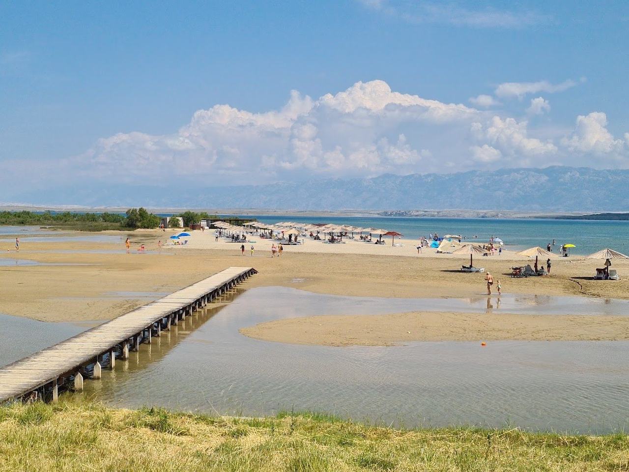 Queens Beach Kraljicina plaza at Nin with a long sweep of sand, shallow water and the Velebit mountains across the bay on the Dalmatian Coast