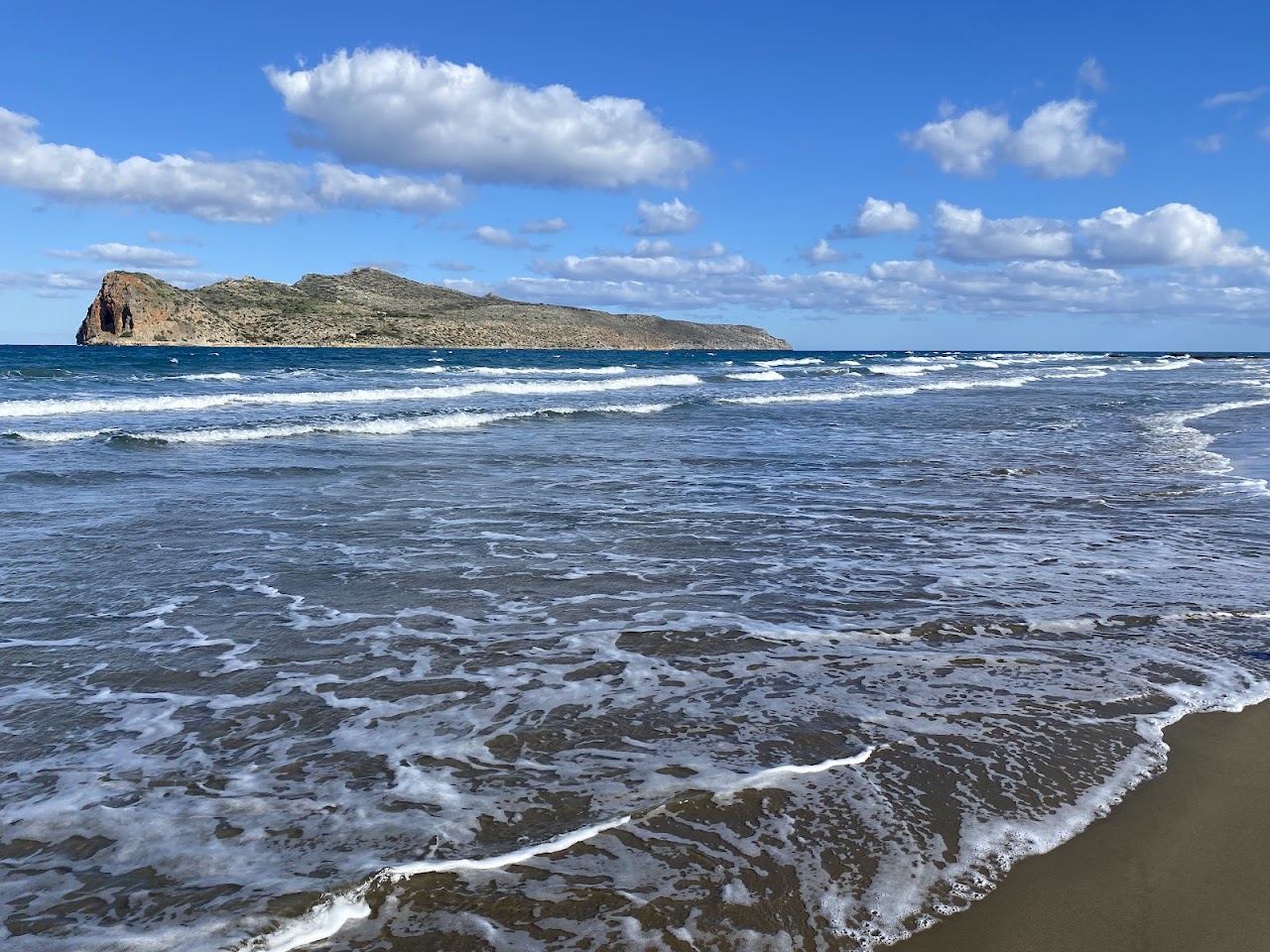 Shallow clear water and long sand at Agia Marina beach on the northwest coast of Crete