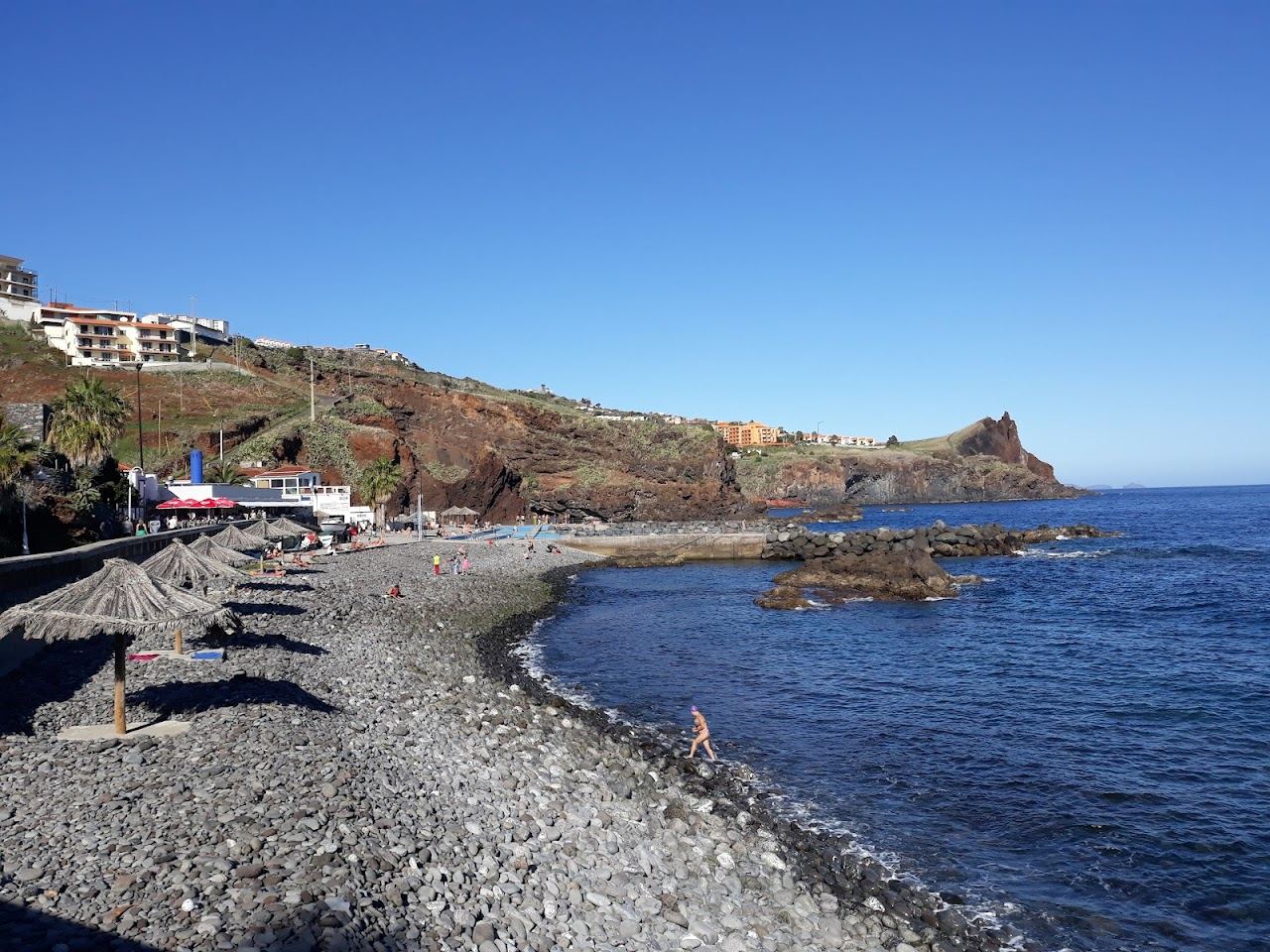 Small pebble cove with clear water and fishing boats at Reis Magos near Canico on the southeast coast of Madeira