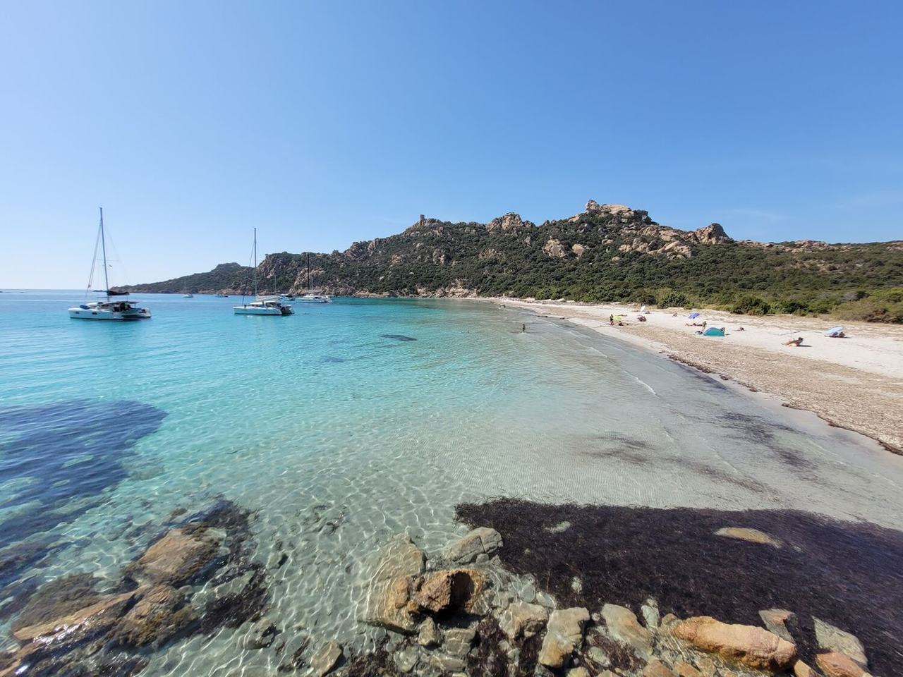 Turquoise water and pale sand at Roccapina Beach in southern Corsica below a rocky ridge
