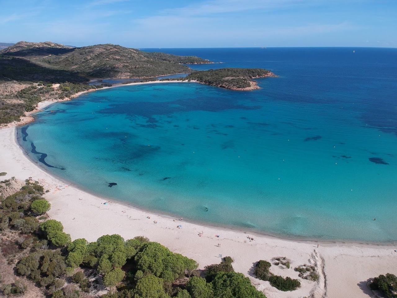 Almost perfect shell shaped bay of white sand and shallow turquoise water at Rondinara in Corsica