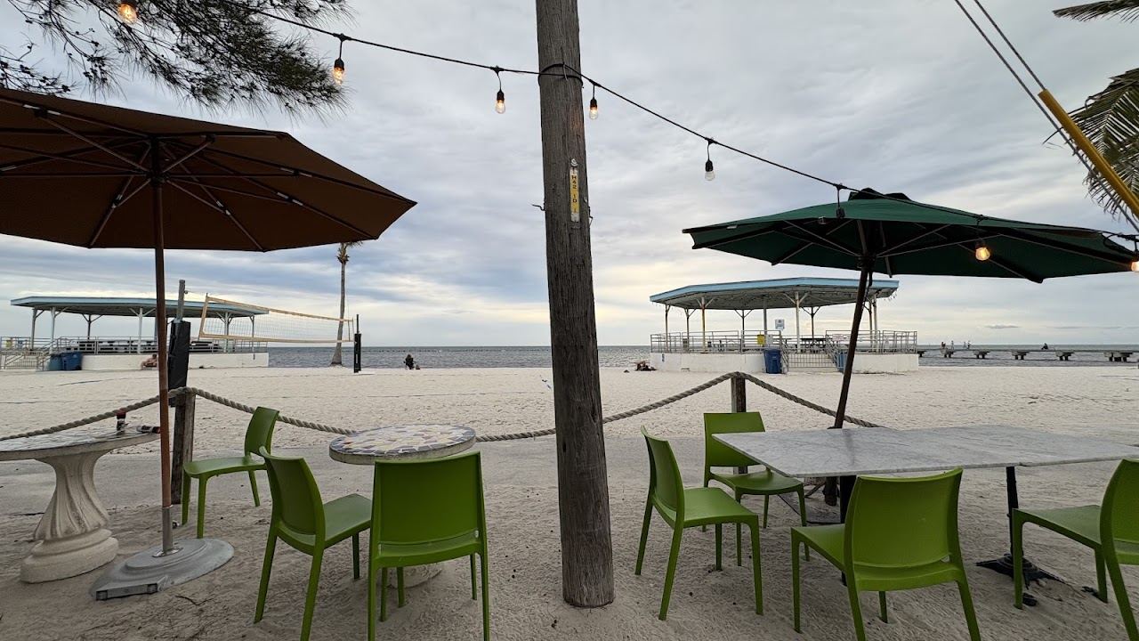 Open air dining tables at Salute! On The Beach facing the sand at Higgs Beach in Key West