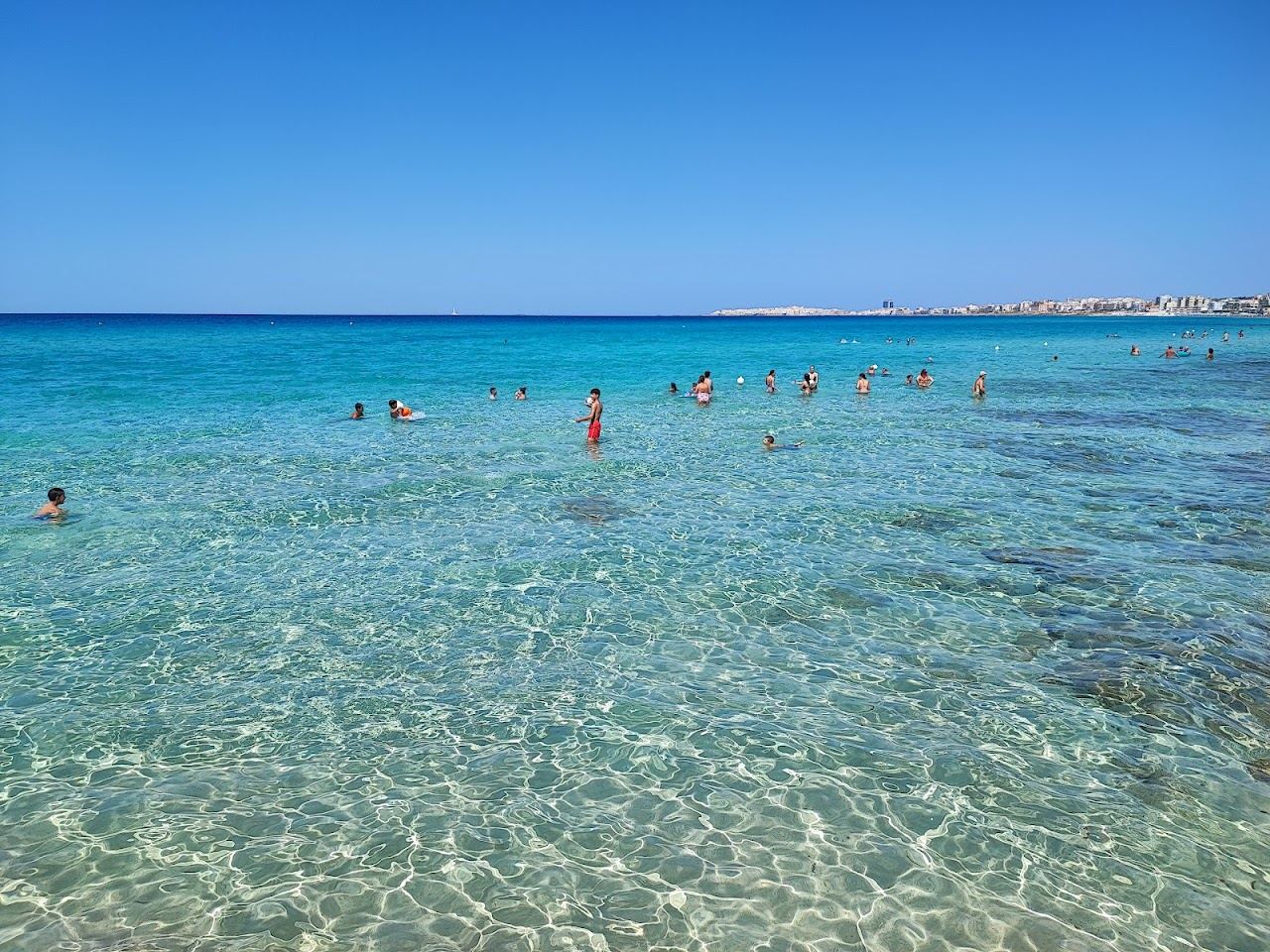 Fine golden sand and shallow turquoise water along Baia Verde beach south of Gallipoli