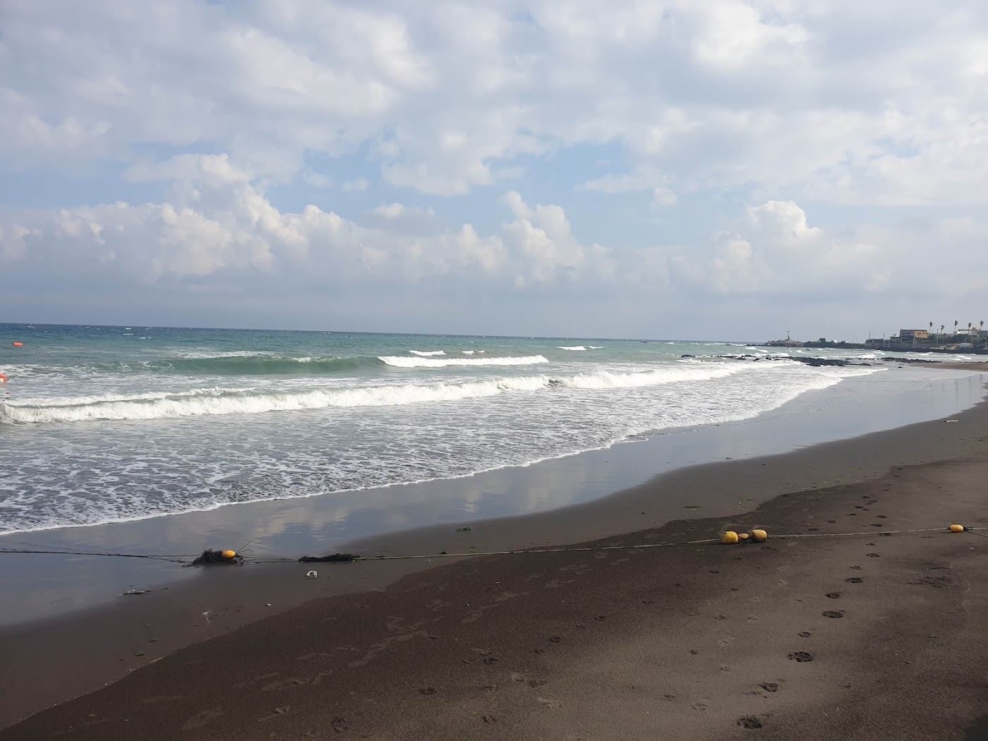 Fine black volcanic sand and calm sea at Samyang Black Sand Beach near Jeju City