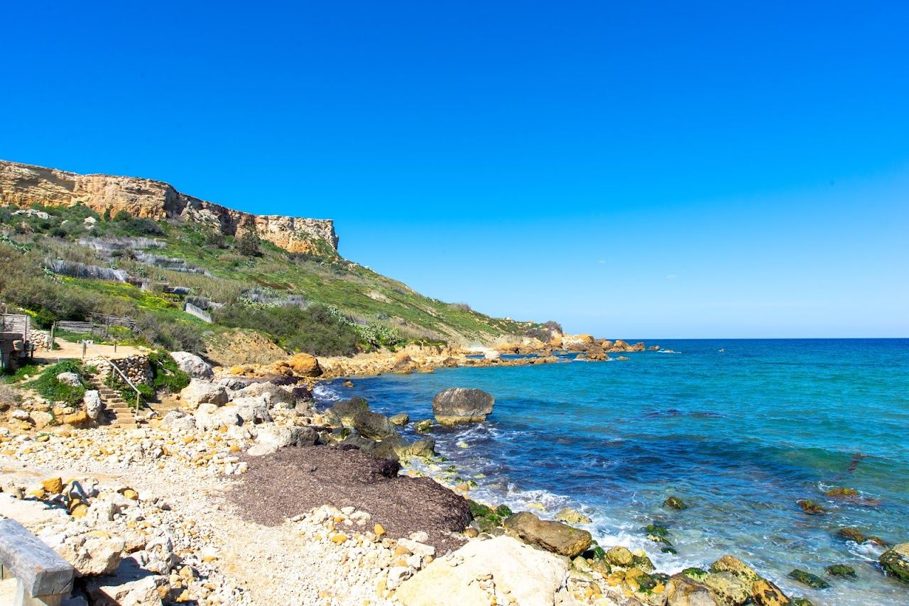 The red gold sand and terraced hills of San Blas Bay in Gozo