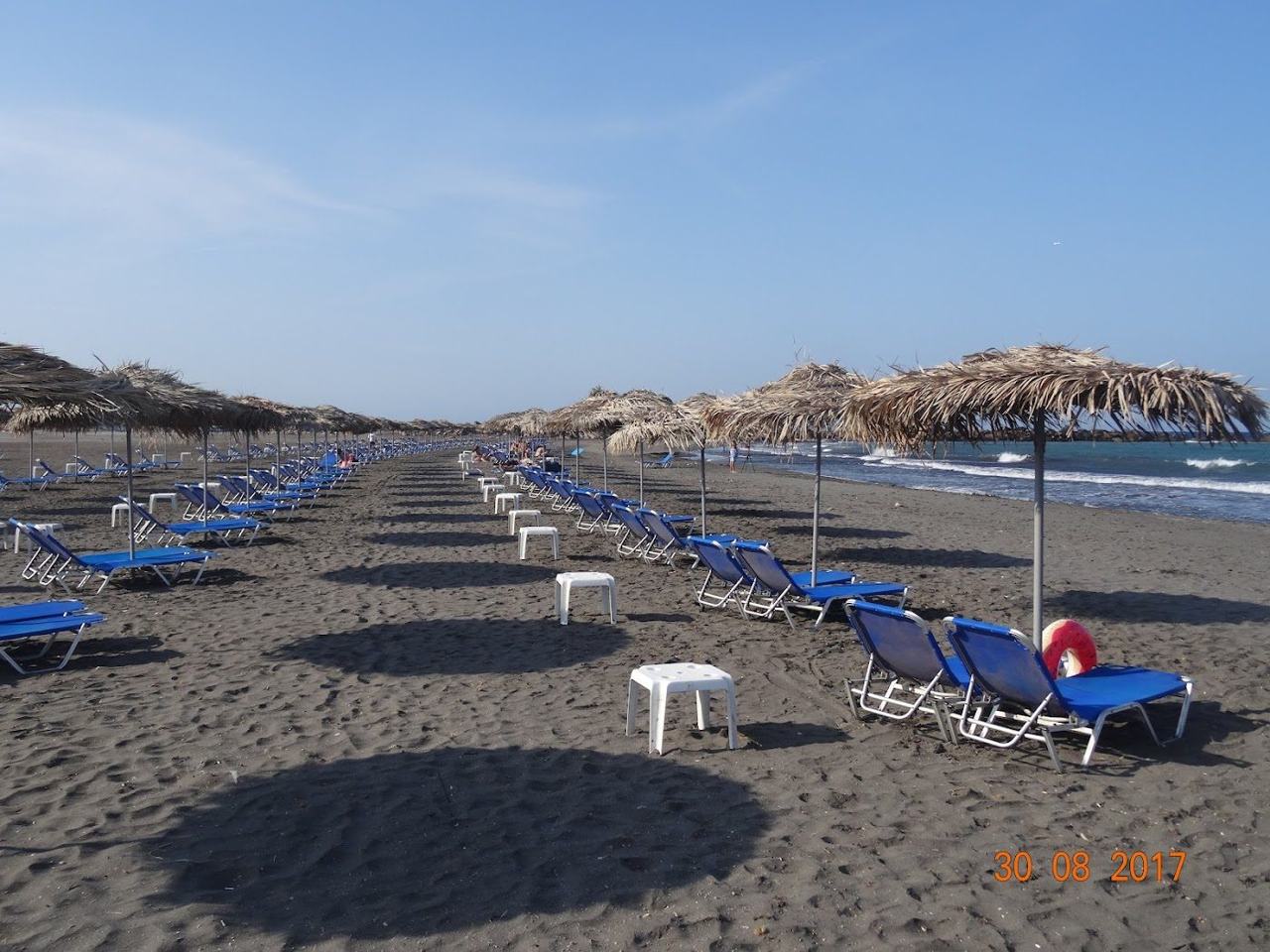 Organised sunbeds on the black volcanic sand at Monolithos beach in Santorini