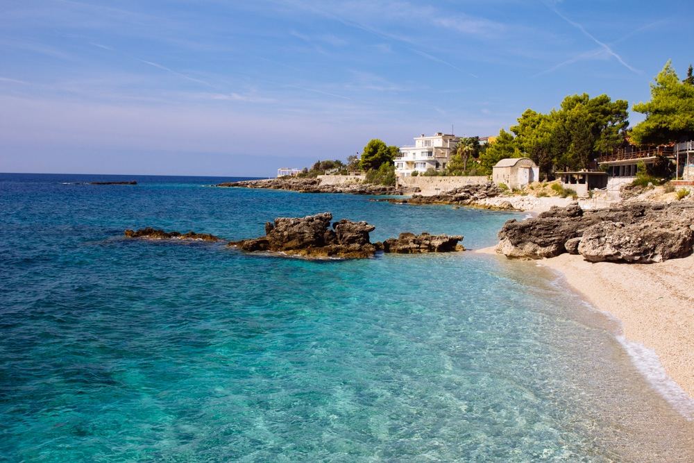 White shingle shore and clear blue Ionian water at Dhermi beach below the Ceraunian mountains