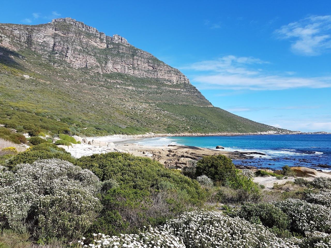 The boulder framed white sand and cold clear Atlantic at Sandy Bay near Cape Town