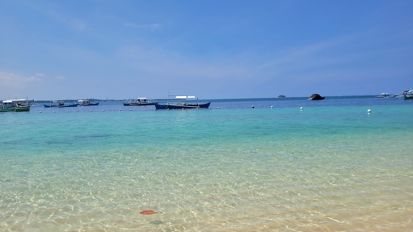 The sheltered, shallow turquoise shallows off a Siargao sandbar island on a calm day