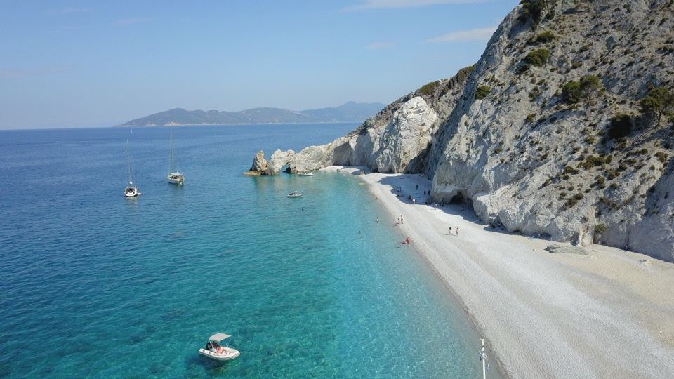 The white pebbles, cliffs and natural rock arch of Lalaria Beach reached by boat in Skiathos