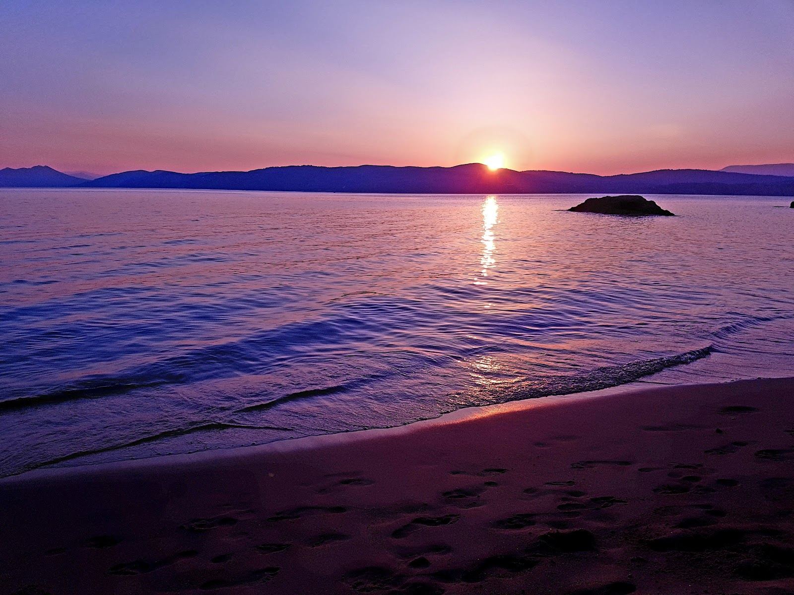 The small quiet cove of Little Banana beach framed by rocks and pines on Skiathos