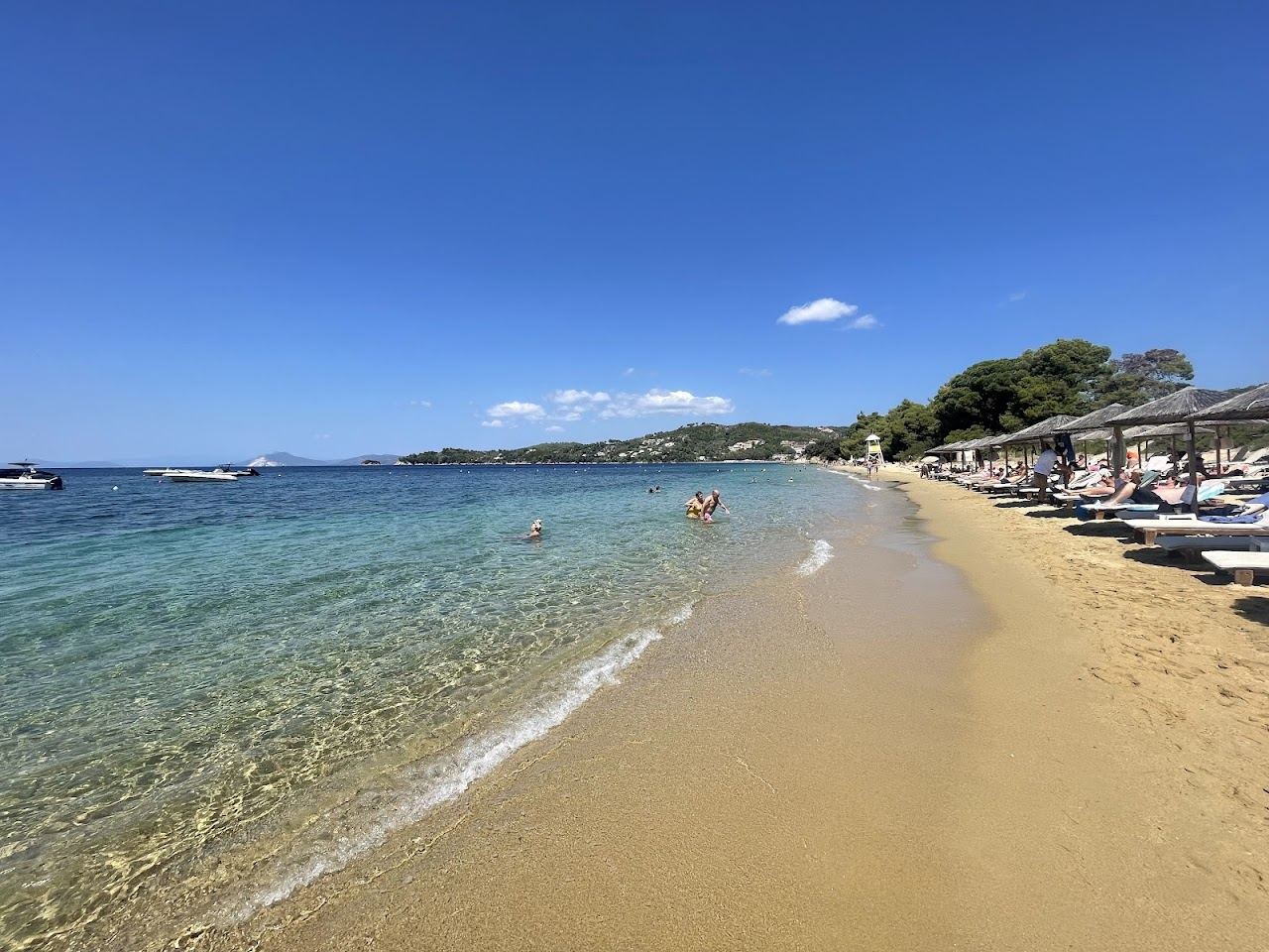The soft sand and clear water of lively Vromolimnos Beach on the south coast of Skiathos