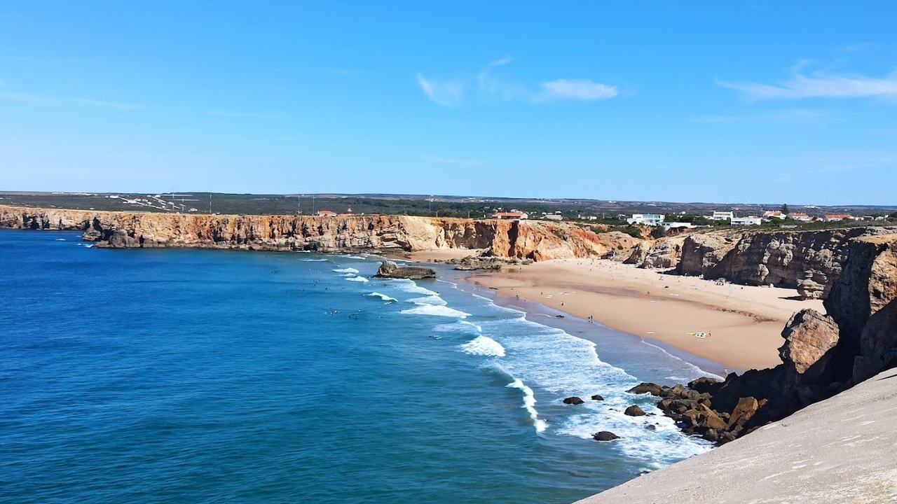 Cliffs and surf glowing gold as the sun sets over the Atlantic on the west of the Algarve