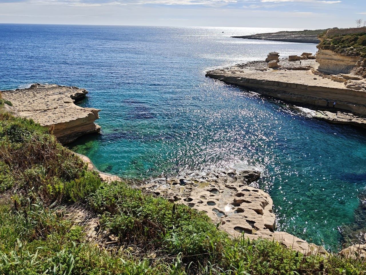 The flat limestone slabs and deep clear water of St Peter's Pool near Marsaxlokk in Malta