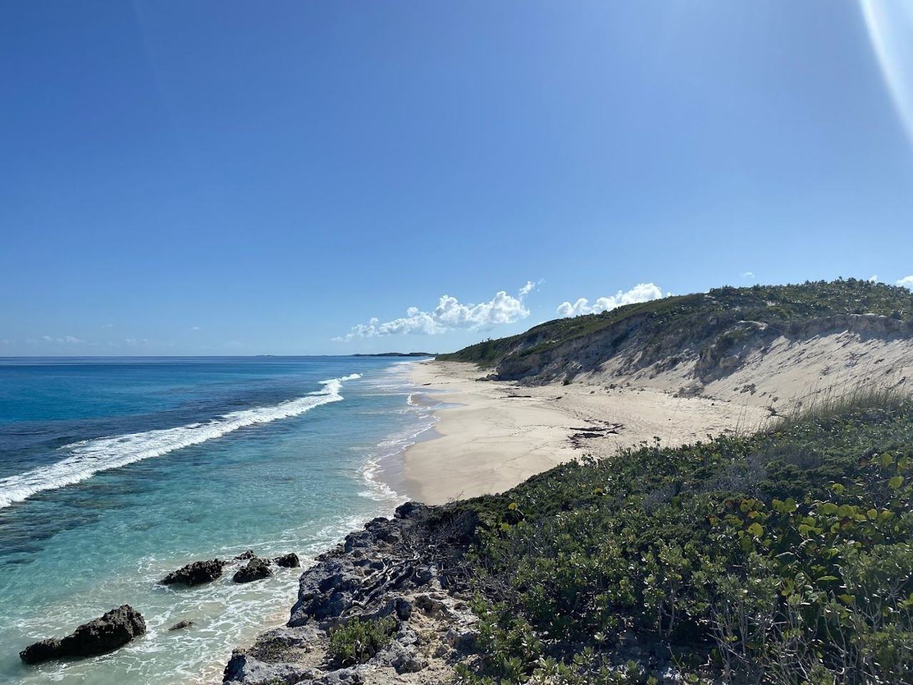 Calm turquoise harbour water and pale sand beach on Stocking Island across from George Town Great Exuma Bahamas