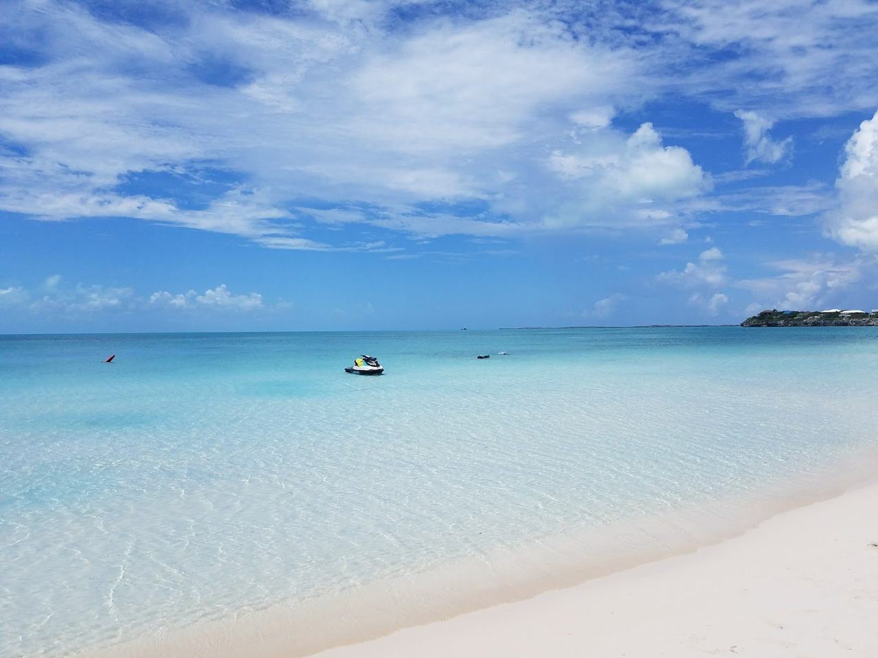 Flat clear turquoise water over white sand on a calm sheltered beach in Turks and Caicos