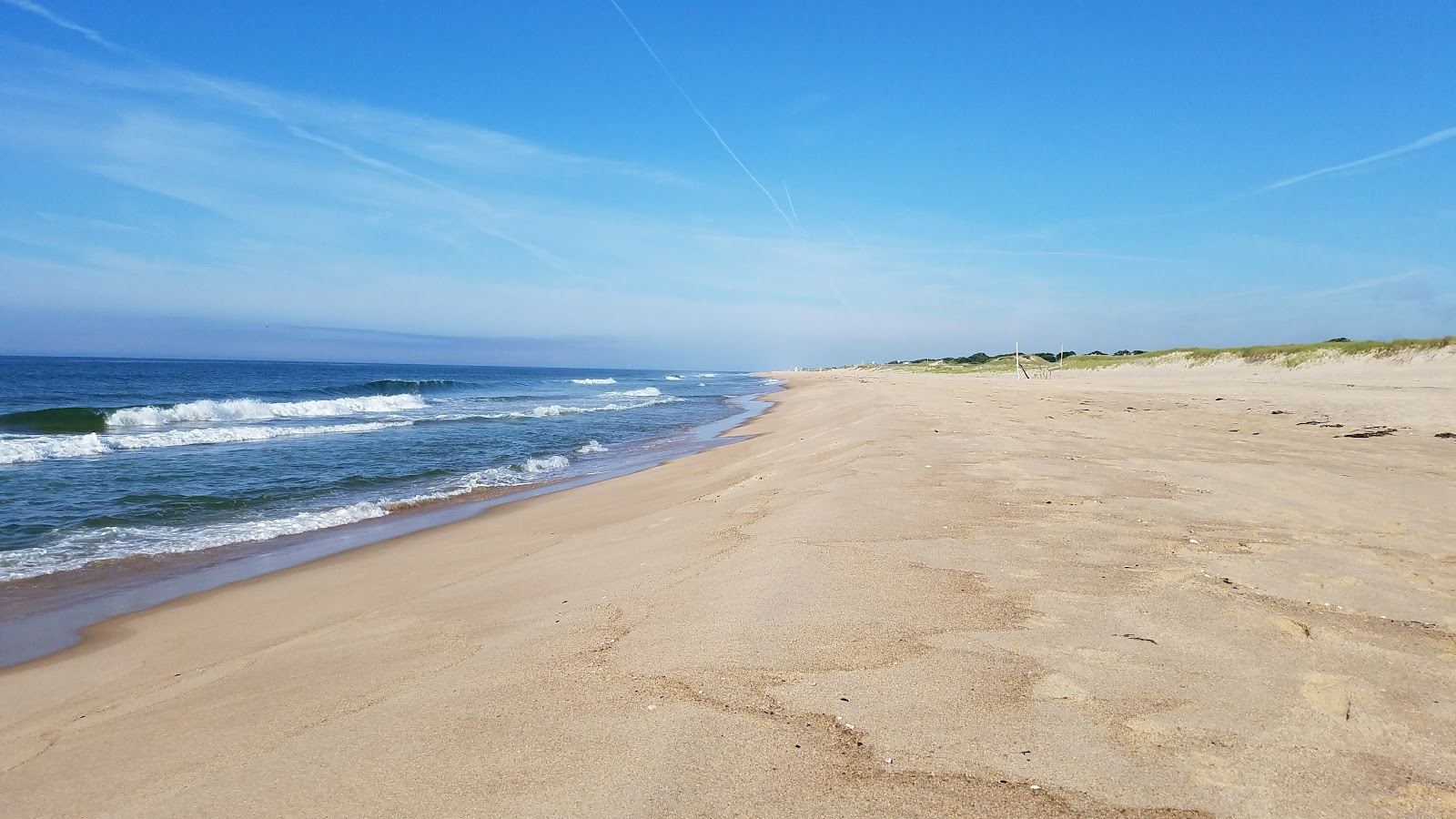 A quiet dune backed Hamptons beach in soft golden evening light for couples