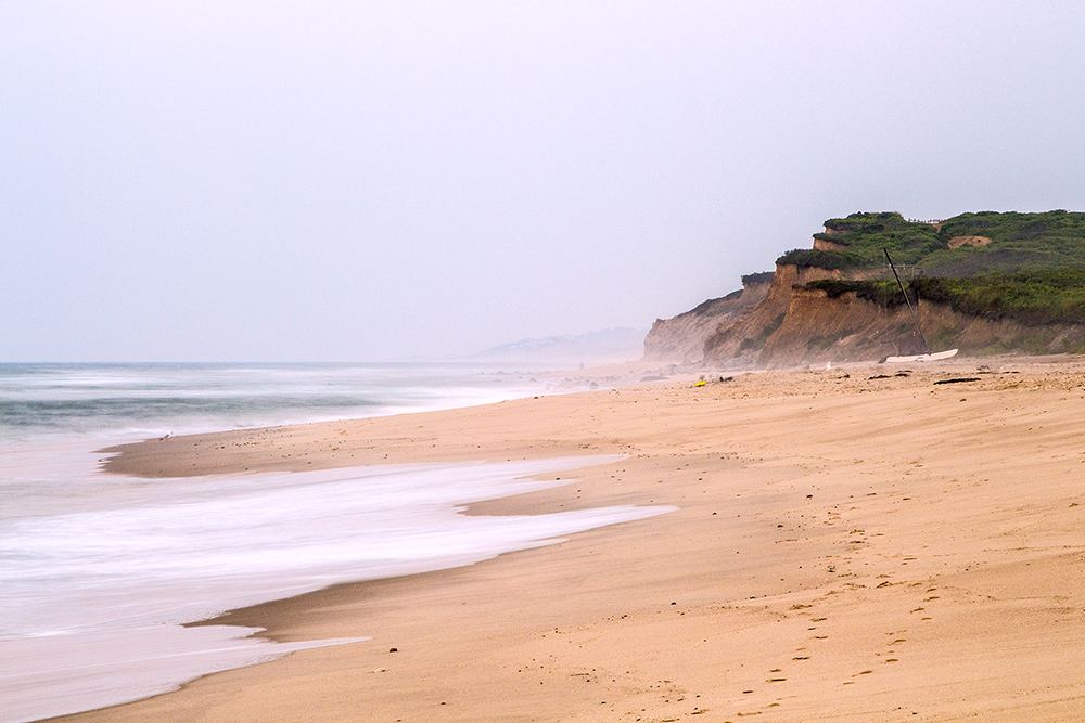 Surfers carrying boards on the open Atlantic sand at Ditch Plains in Montauk