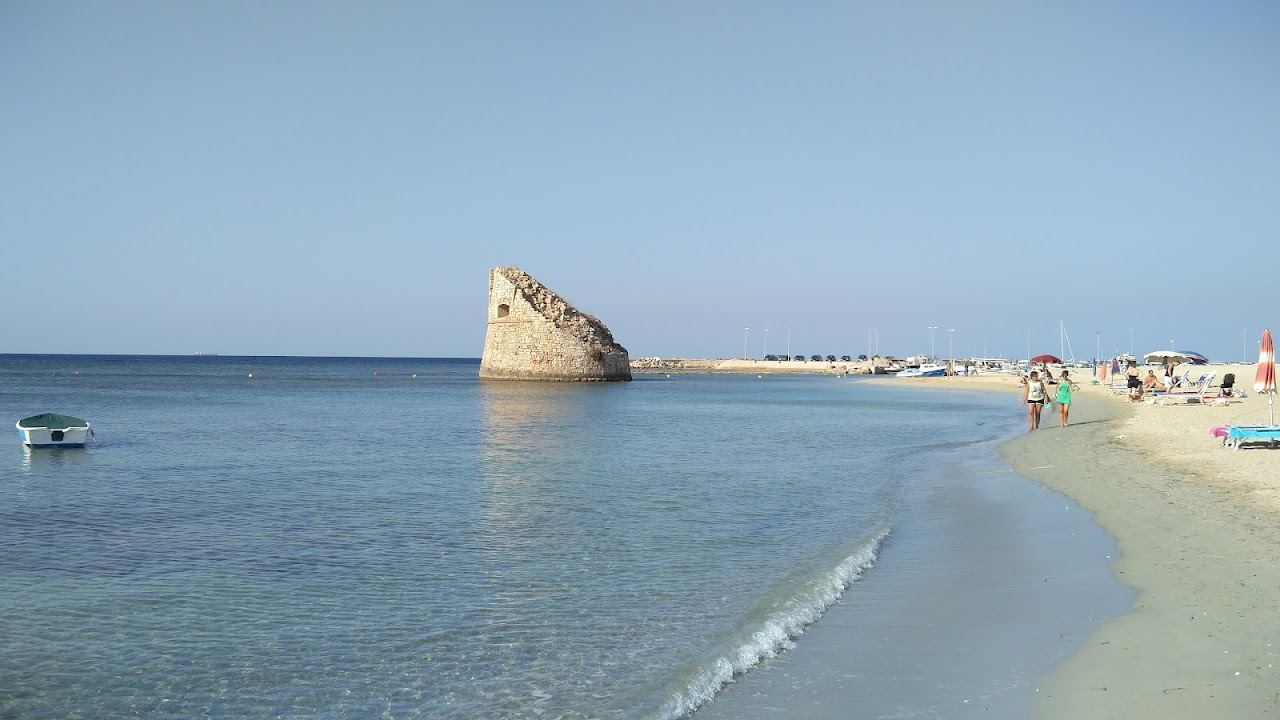 Shallow sandy beach at Torre Pali with the ruined tower standing offshore in the sea, deep Salento, Puglia